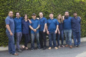 A group of employees posing together outdoors in matching blue shirts.