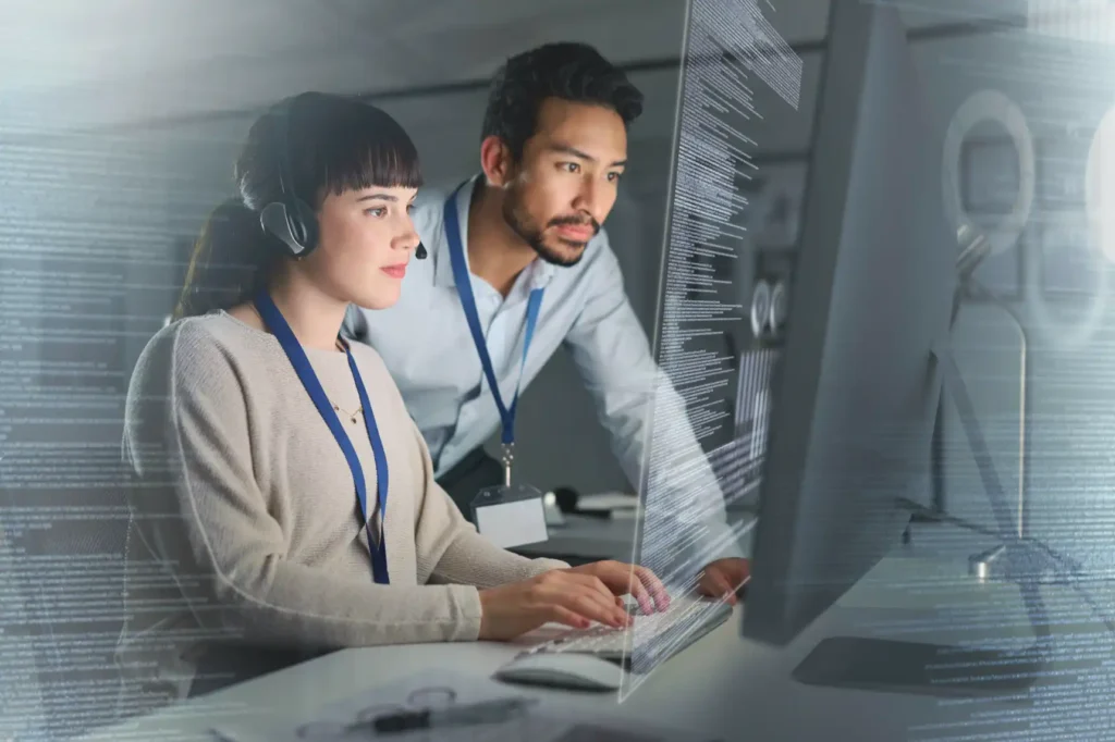 Customer support or IT staff working with code on a large transparent screen.
