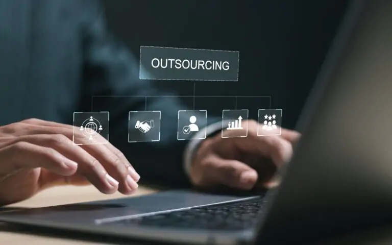 IT outsourcing image of hands on a laptop with a holographic interface displaying icons for global reach, collaboration, and growth. benefits of outsourcing it services